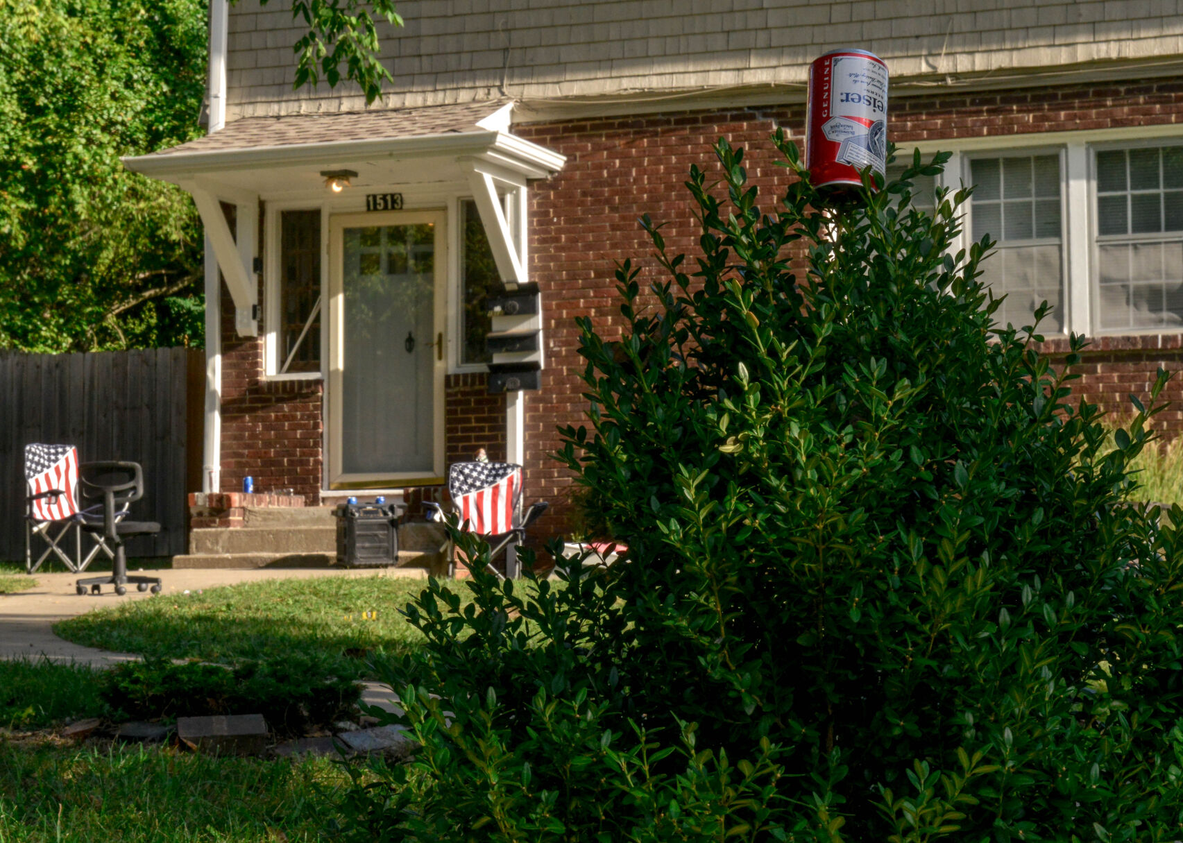 An empty beer can adorns the front bushes of an East Campus house